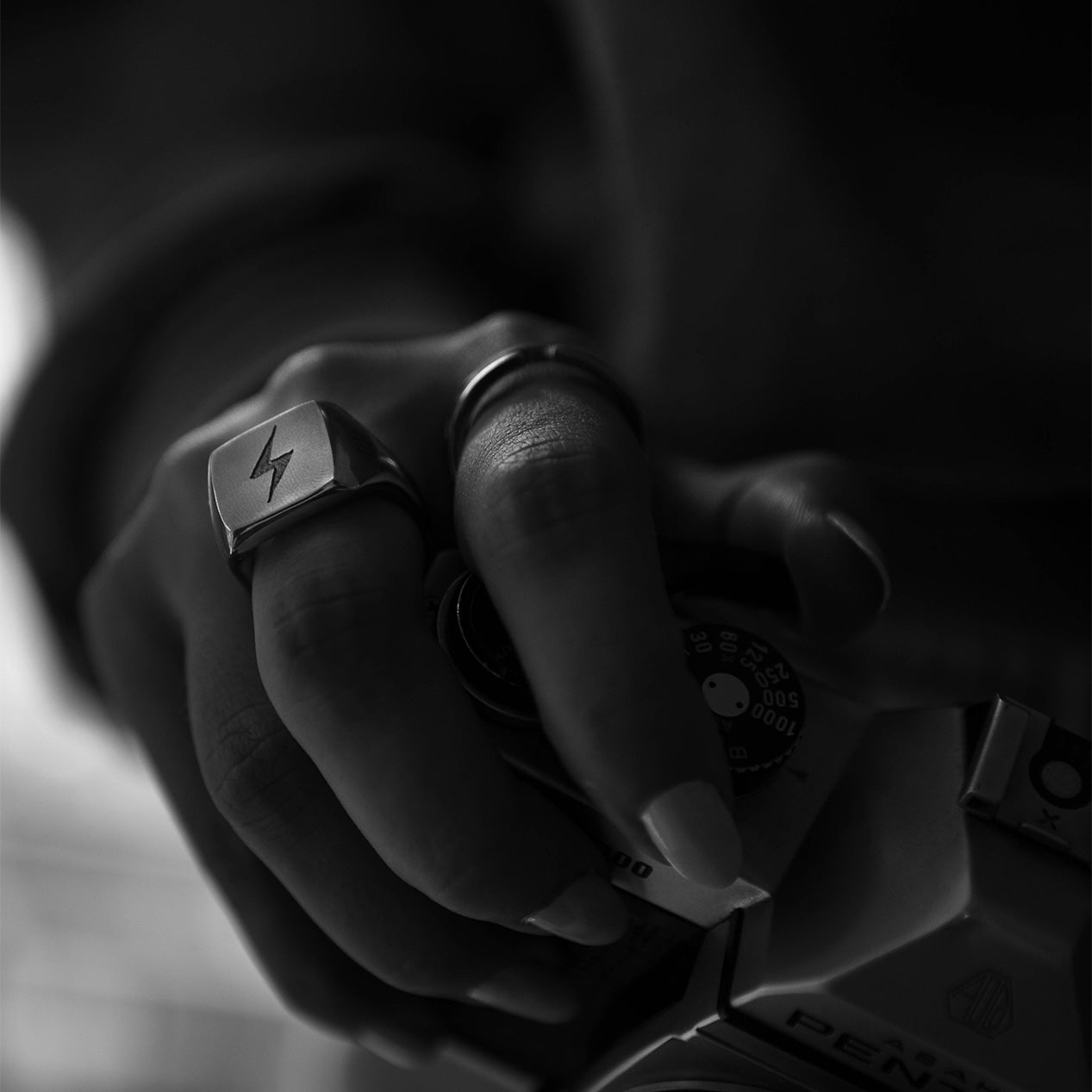 Closeup of a hand holding a camera while wearing two titanium rings-