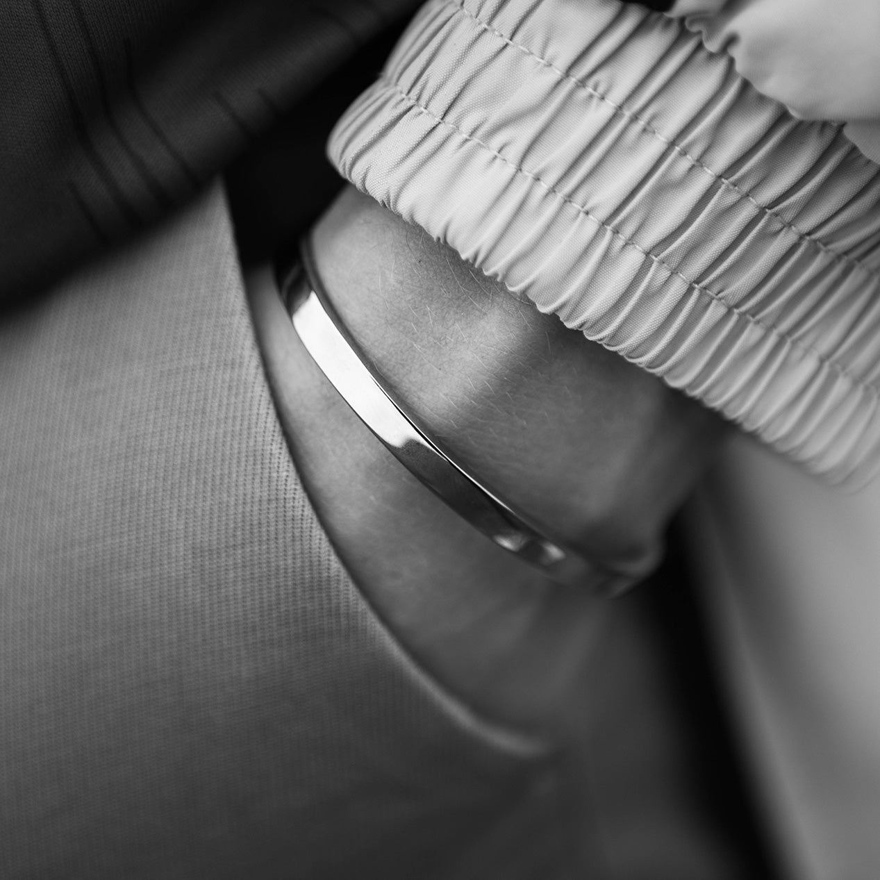 Closeup of a hand in a pocket wearing a titanium bracelet on the wrist.