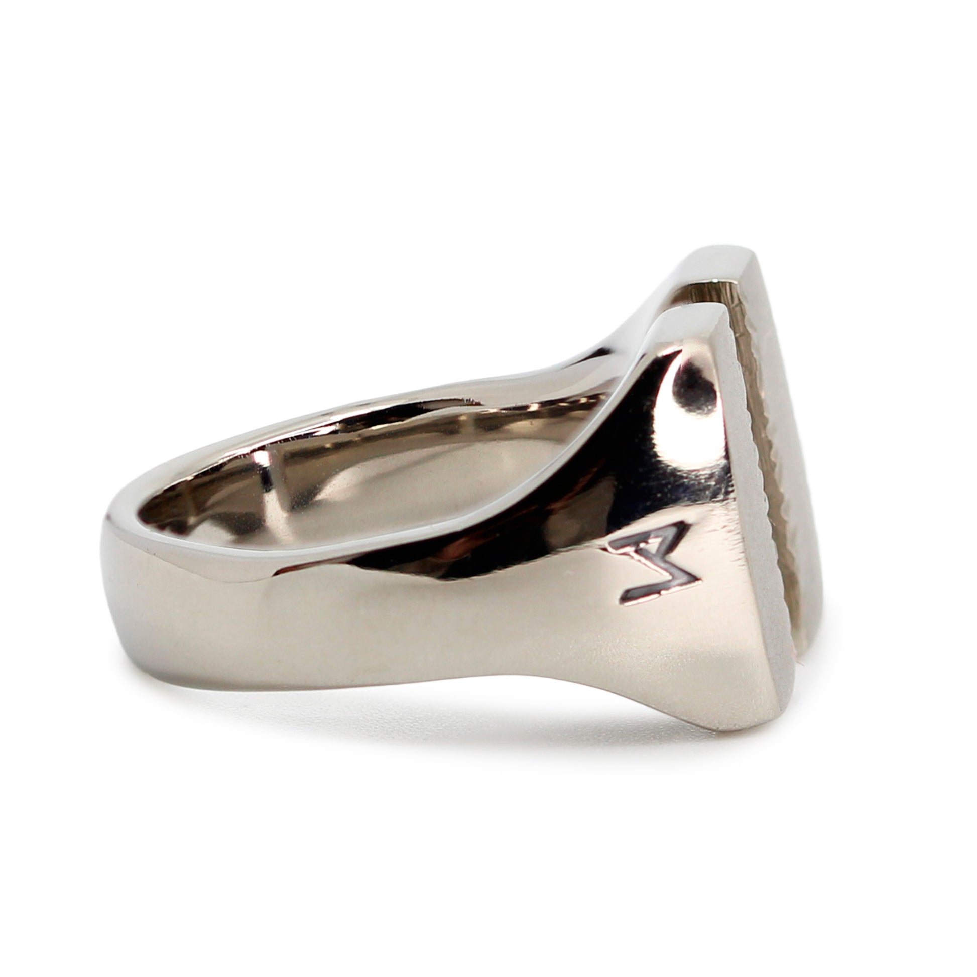 Single silver-colored titanium signet ring, 15x15 mm wide surface which has been cut through the middle. Image shows side view of the ring
